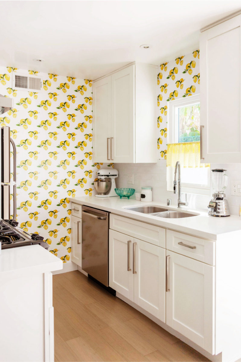 White kitchen na may dilaw na wallpaper