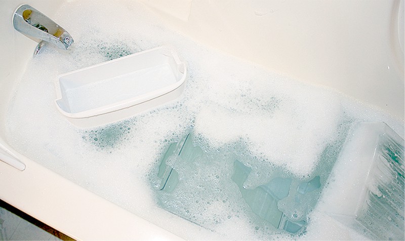 Moczenie zdejmowanych części lodówki w wannie